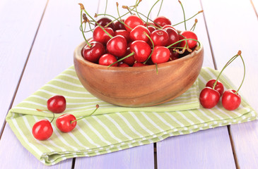 Cherry berries in bowl on wooden table close up