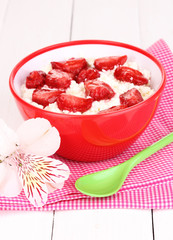 Cottage cheese in red bowl with sliced strawberries