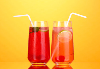 Two cherry cocktails with ice on orange background