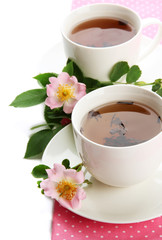 Cups of herbal tea with hip rose flowers, isolated on white