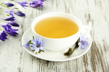 Cup of tea with chicory, on wooden background