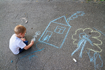 Boy drawing house and tree with chalk