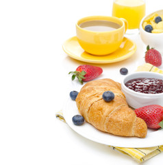 Breakfast with croissant, jam, fresh berries, coffee with milk