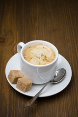 cup of black coffee with foam and cane sugar cubes