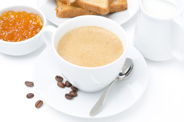 cup of cappuccino, milk, fresh toast and jam on white background