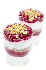 layered dessert made of yogurt, granola and cherry on a white