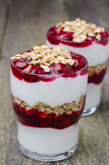 layered dessert with yogurt, granola and cherry on wood