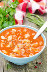 tomato soup with pasta, beans and rosemary in blue bowl