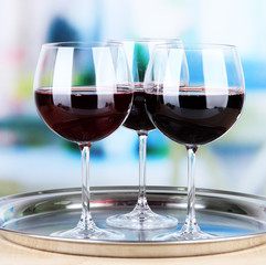 Wine glasses on  tray, on bright background