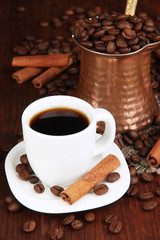 Coffe cup and metal turk on wooden table