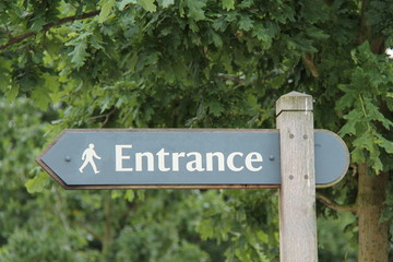 A Sign Post Pointing to a Pedestrian Entrance.