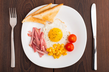 Fried egg with toasts, ham and cherry tomato