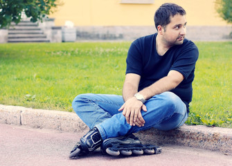 a young man sitting  in roller-skates