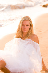 Fototapeta na wymiar Woman wrapped in wedding veil on the beach