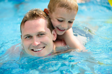 Young father and little son swimming in pool