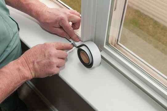 A Worker Installs Insulation In Window.