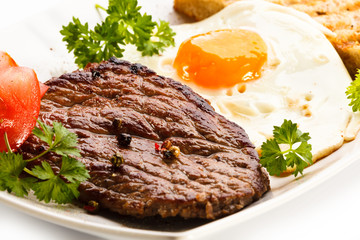 Grilled steak, toast, fried egg and vegetables