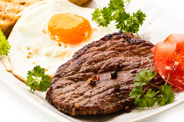 Grilled steak, toast, fried egg and vegetables