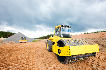 Soil compactor and bulldozer during road construction works