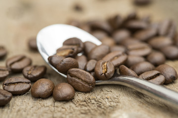 Coffee beans and spoon on wooden background