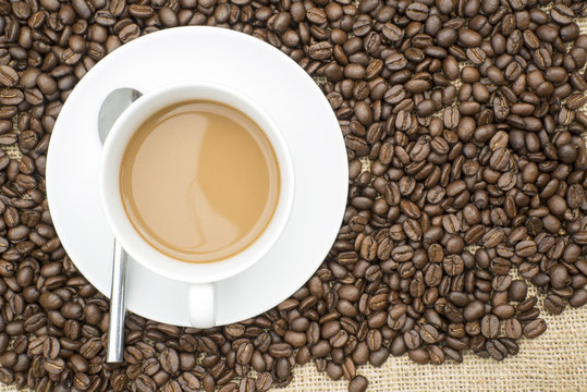 Cup of coffee and coffee beans on hessian background