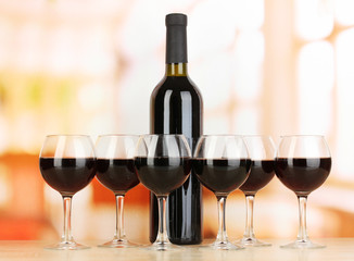 Red wine in glass and bottle on room background