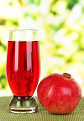 Glass of fresh garnet juice on table on bright background