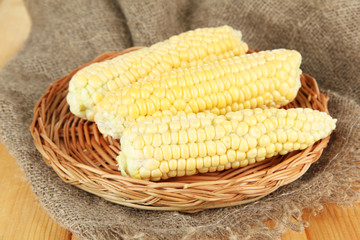 Fresh corn on wicker mat, on sackcloth background