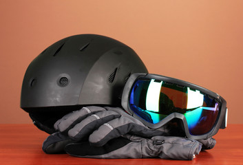 Winter sport glasses, helmet and gloves, on brown background