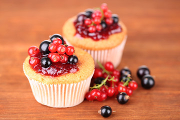 Tasty muffins with berries on wooden background