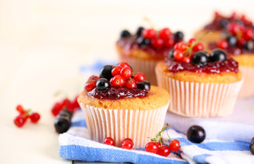 Tasty muffins with berries on white wooden table