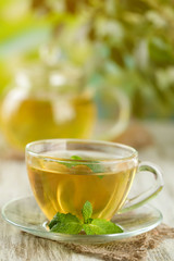 Cup of herbal tea with fresh mint flowers on wooden table