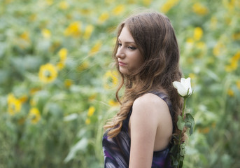 Naklejka premium Romantic woman with rose lying on sunflowers field