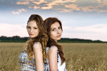 Two young beautiful girls in field with wildflowers flowers, out