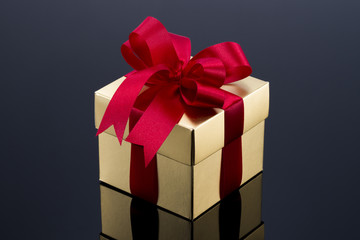 Beautiful gold present box with red bow and ribbons