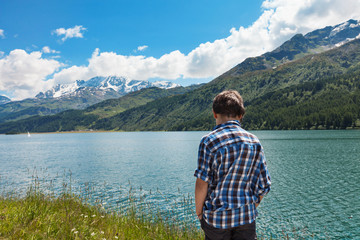portrait of boy on the shore of a mountain lake, back view