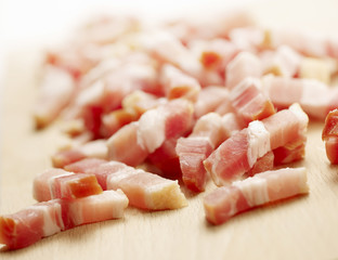 raw diced bacon on a wooden cutting board