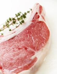 raw steak with thyme on a white cutting board