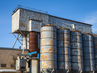 Row of gray tall tanks on old concrete factory