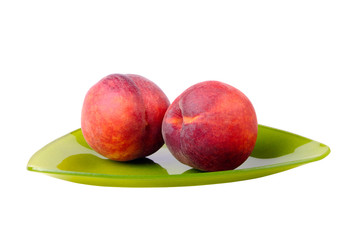 Two peaches on a green plate