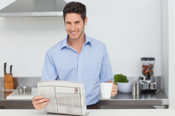 Man reading a newspaper and holding a cup of coffee