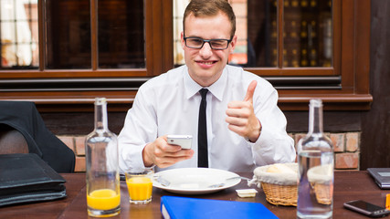 Smiling Businessman sitting  in restaurant. Thumb up.