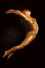 acrobat dancer toned in gold  jumping over black background