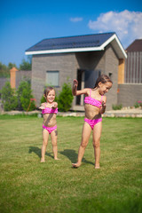 Fototapeta premium Two little sisters frolicing and splashing in their yard