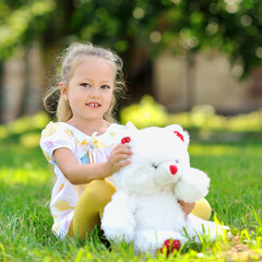 Sweet little girl outdoors with a toy bear