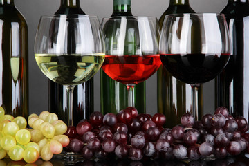 Assortment of wine in glasses and bottles on grey background