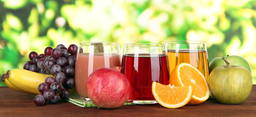 Glasses of fresh juice on table on bright background