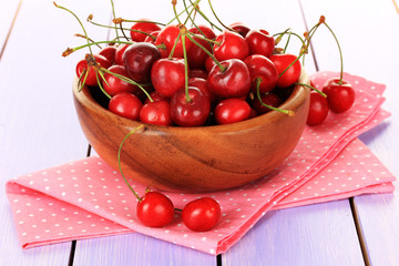Cherry berries in bowl on wooden table close up