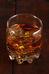 Brandy glass with ice on wooden background