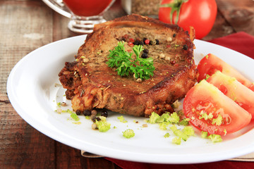 Piece of fried meat on plate on wooden table close-up
